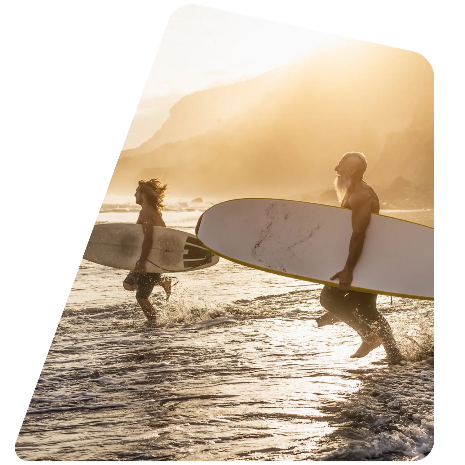 Two surfers walking into the water at sunset